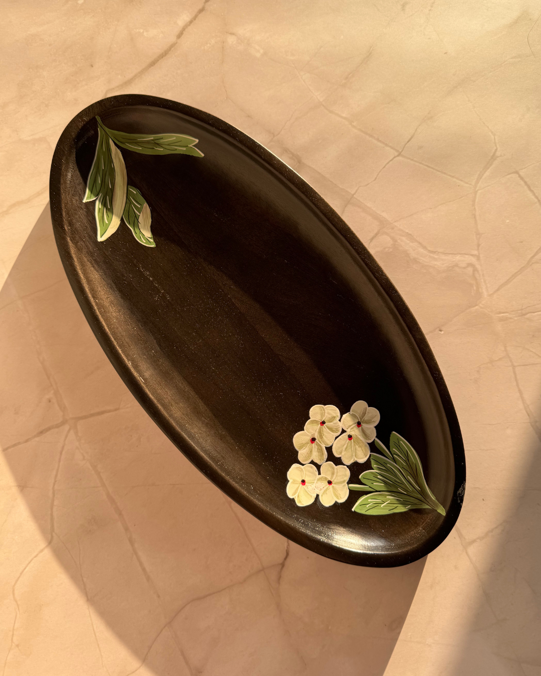A platter that represents the Desert flower Vinca which is ideal as a gift, home decor, serve ware, dinner ware, kitchen and table decor. Made from mango wood which boasts sustainability and eco-friendly option. Durable and easy to clean.
